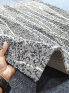 Abstract area rug with speckled navy and gray pattern, angled corner view