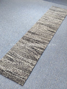 Slim abstract runner rug with layered stripe pattern in speckled light and dark gray