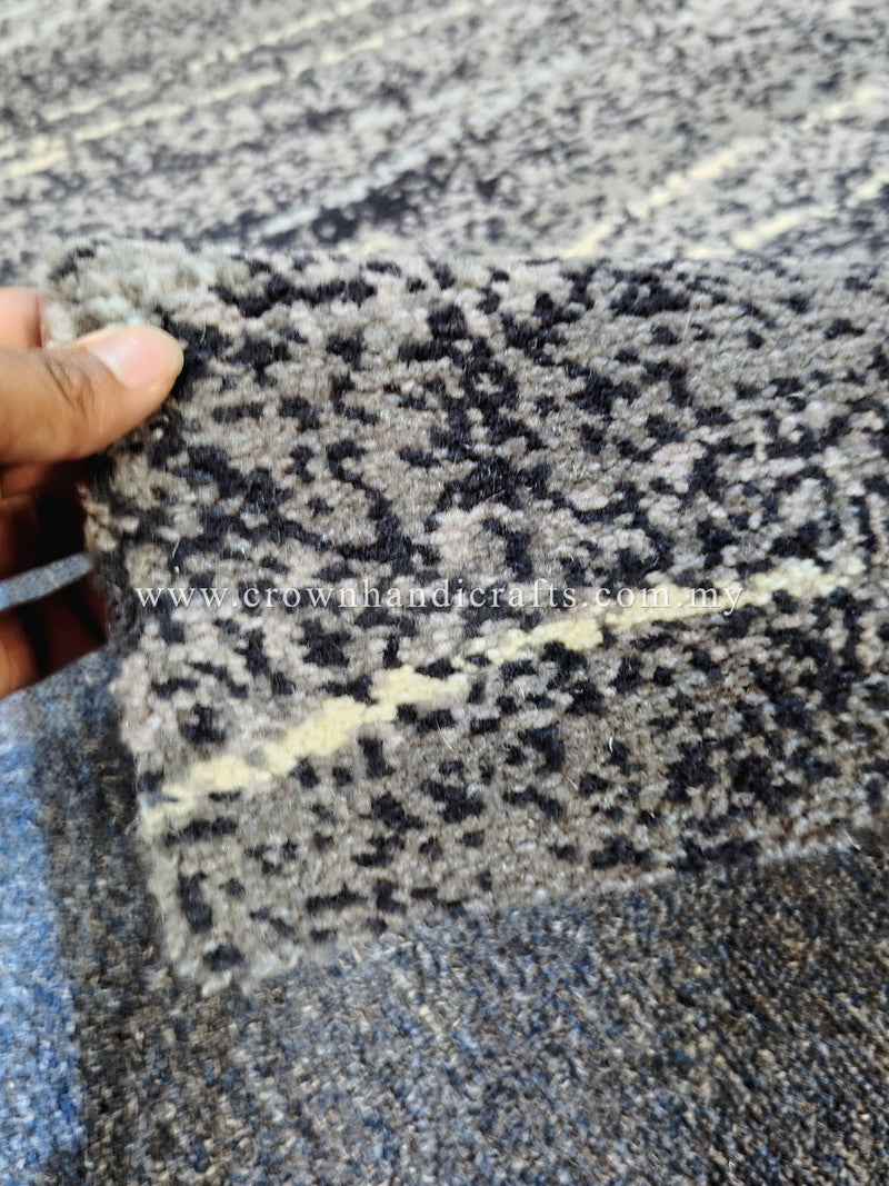 Hand holding edge of abstract runner rug; speckled gray pattern with short stripe lines