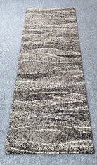 Hallway runner rug in beige and dark speckled abstract stripes with short, dense border