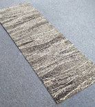 Hallway runner rug with beige background and dark speckled abstract stripe pattern, short pile
