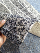 Abstract runner rug corner close-up, textured pile with gray and white abstract pattern