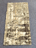 Compact grey mat rug, beige surface with dark patchwork-style abstract motif