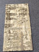 Compact grey mat rug, centered distressed pattern in beige with dark highlights