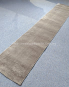 Hallway runner rug viewed diagonally, beige tone with muted mottled striping