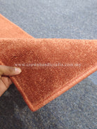Hand holding rust velvet runner rug corner, soft short pile and edge trim