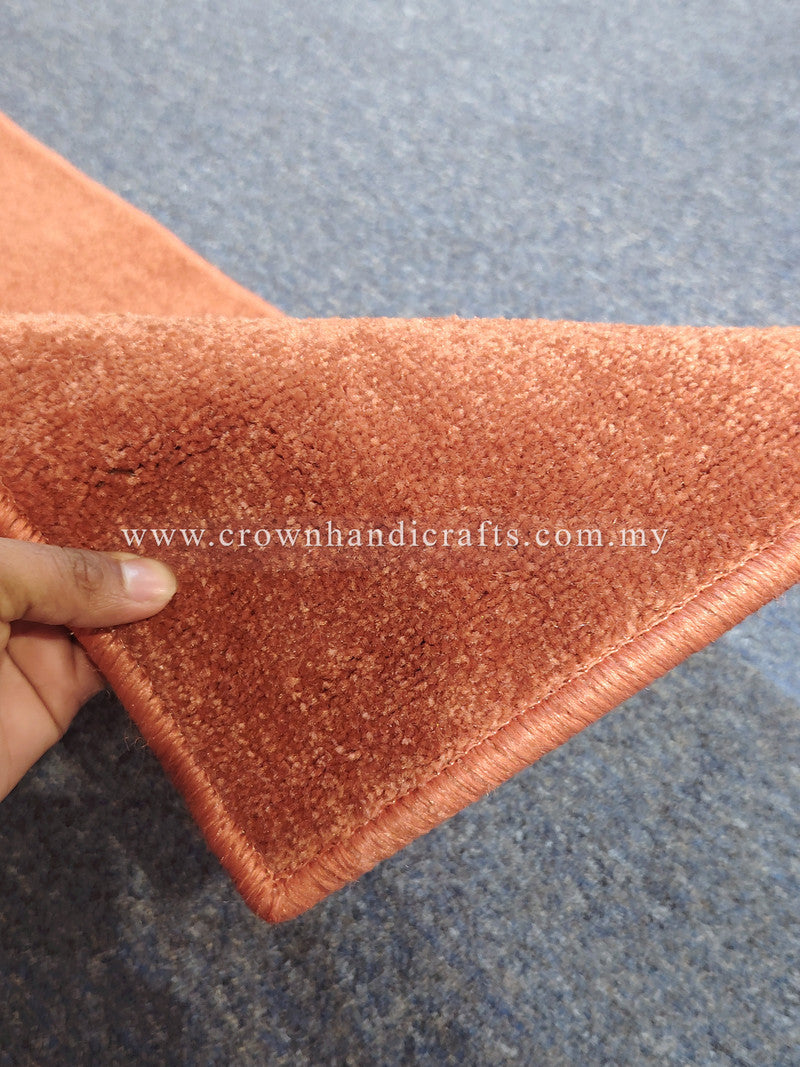 Hand holding rust velvet runner rug corner, soft short pile and edge trim