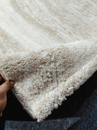 Cream area rug with dense short shag pile and textured abstract pattern