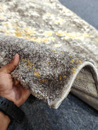 Hallway runner rug close-up: grey pile with yellow flecks and stitched border edge