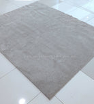 Plush area rug with uniform short pile in light gray-beige on smooth floor
