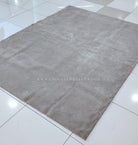 Plush rectangular area rug with soft short pile in light gray-beige, flat lay