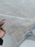 Plush area rug edge with short dense pile, light beige tone and rounded corner