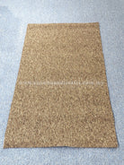 Tan-brown rectangular rug with low pile texture and simple flat border