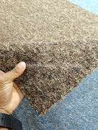 Brown textured rug corner detail with visible low pile texture and backing
