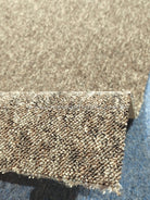Rectangular textured rug corner close-up, dense loop pile and short frayed binding