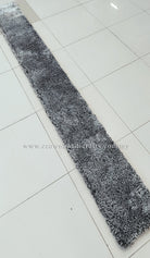 Narrow shaggy runner rug with black-and-white mottled pile, laid on floor