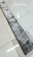 Narrow shaggy runner rug with mottled black-and-white texture, flat on floor