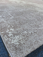Abstract area rug with distressed beige and white texture, bound corner detail.