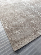 Abstract area rug with distressed beige and white surface, corner and border shown.