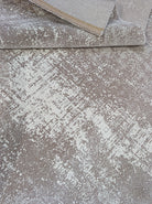 Abstract area rug with distressed beige and white pattern, binding edge detail.