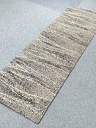 Abstract runner carpet with beige horizontal stripe bands and dark speckled texture.