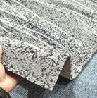 Abstract runner carpet, beige and dark speckled surface with stripe pattern, rolled edge.