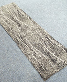 Abstract narrow runner rug with beige and gray mottled stripe pattern, flat on floor