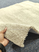 Plush beige comfort mat with shaggy pile; hand holds curled corner for thickness