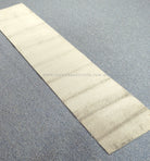Cream-beige runner rug laid flat with minimal texture and straight stitched edges