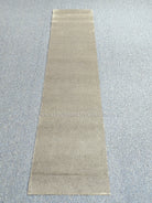 Beige runner rug laid flat with simple solid design and low, even texture