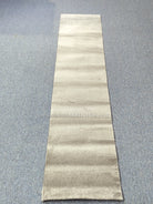 Beige runner rug laid flat with horizontal tonal stripe bands and low pile texture
