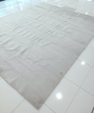 Large oatmeal-beige area rug laid out flat with textured, plush pile