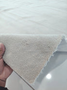 Oatmeal-beige rug corner showing thick plush pile and fringe edge