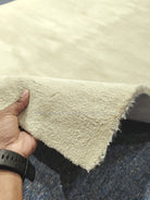 Cream runner rug corner with short shag pile and frayed backing edge