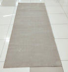 Oatmeal beige long area rug laid flat, low pile with neat, straight border