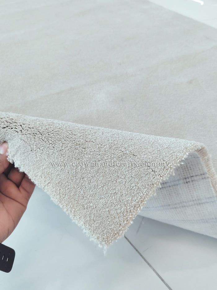 Oatmeal beige area rug edge held up, showing short fringe and soft shag pile
