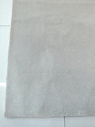 Oatmeal beige textured area rug with even low pile and straight border edge