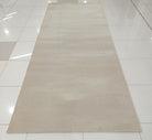 Long cream area rug laid out flat with uniform texture across the surface