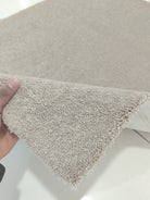 Soft brown shag rug corner detail with dense pile, edge held by hand