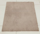 Light brown rectangular shaggy rug with even short pile and stitched border.