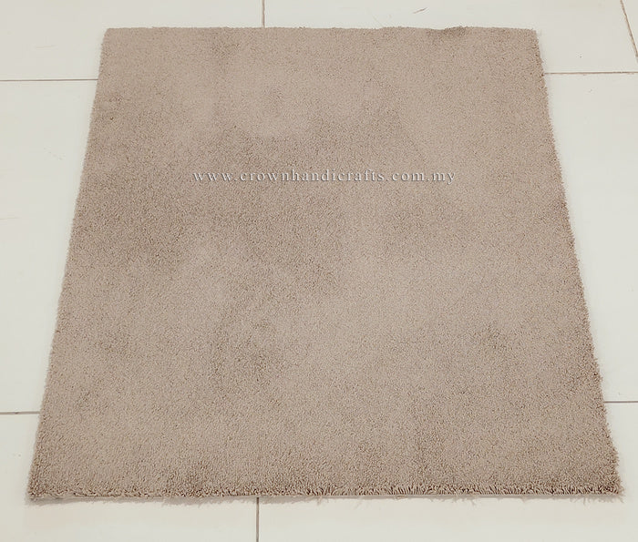 Light brown rectangular shaggy rug with even short pile and stitched border.