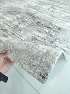 Grey and cream distressed area rug corner, soft pile texture