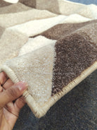 Bone and brown runner rug with geometric patchwork pattern and stitched border.