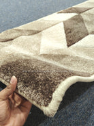 Textured bone and brown runner rug corner with stitched edging and geometric shapes.